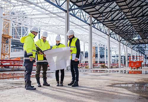 project managers discuss a blueprint in a real estate development under construction